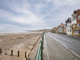 A beach with a road and houses at Beachside Cottage in Sandsend
