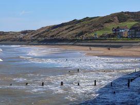 A beach with water and cliffs at Beachside Cottage in Sandsend