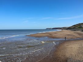 A beach with sand and ocean waves at Beachside Cottage in Sandsend