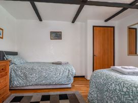 A bedroom with two single beds with patterned bedspreads a wooden door a wooden chest of drawers and a wall mirror at Rock Cottage in Portmellon near Mevagissey