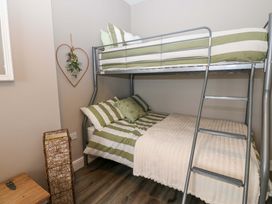 A bunk bed with green and white bedding in a bedroom at Amblers Rest in Amble