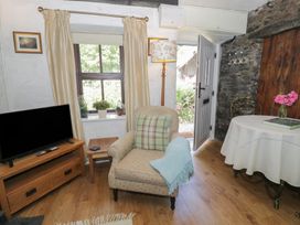 A living room with an armchair and television at Squirrel Cottage in Betws-Y-Coed