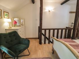 A bedroom featuring a chair, table with lamp and flowers at Squirrel Cottage in Betws-Y-Coed