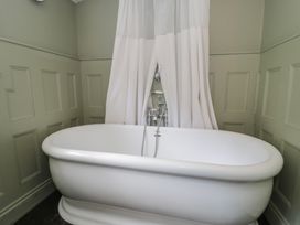 A bathtub with a shower curtain at Squirrel Cottage in Betws-Y-Coed
