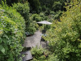 A garden with a table and chairs under an umbrella at Squirrel Cottage in Betws-Y-Coed
