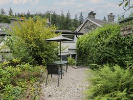 A garden with a table and chairs under an umbrella at Squirrel Cottage in Betws-Y-Coed