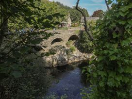 A bridge over a river with trees and people at Squirrel Cottage in Betws-Y-Coed
