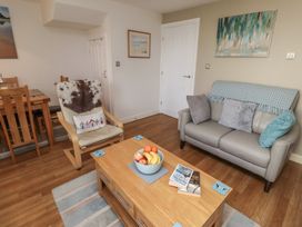 A living room with a sofa, armchair, coffee table, and dining area at Tidal Watch in Seahouses
