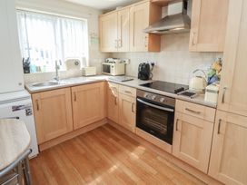 A kitchen with cabinets, stove, sink, and appliances at Tidal Watch, Seahouses