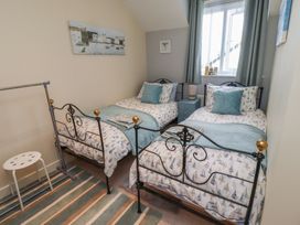 A bedroom with two beds and a bedside table at Tidal Watch in Seahouses