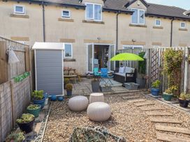 A garden with a shed, table, chairs, and flower pots at Tidal Watch in Seahouses