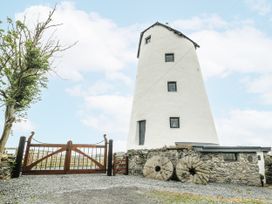 An outdoor view of a windmill with wooden gates at The Old Cornmill in Cemaes Bay