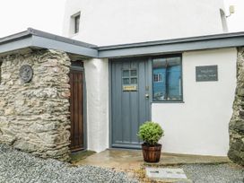 An entrance with a grey door and stone wall at The Old Cornmill in Cemaes Bay