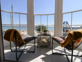 A sunroom with chairs and a table overlooking the beach at The Beach Condo in Weymouth