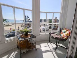 A sunroom with a chair and table overlooking the beach at The Beach Condo in Weymouth