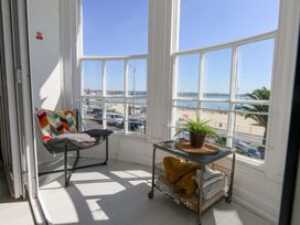 A balcony with a chair and table overlooking the beach at The Beach Condo in Weymouth