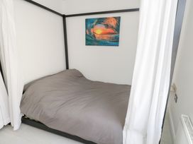 A bedroom with a canopy bed and painting on the wall at The Beach Condo in Weymouth