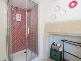 A shower with glass doors and decorative items at Old Farm Cottage in Warminster