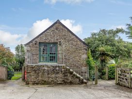 A stone building with a green door at the top of stairs surrounded by plants at The Loft in Bodrean near Truro