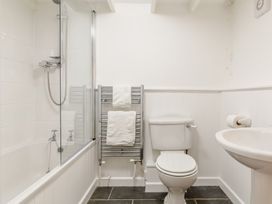 A bathroom with a bathtub shower combination a towel rack with white towels a toilet and a sink at The Loft in Bodrean near Truro