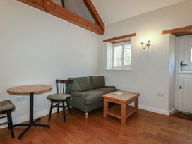 A living room with a green sofa a wooden coffee table two chairs and a small round table at The Copper House in Bodrean near Truro