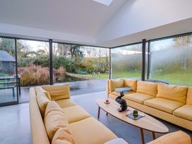 A conservatory with a sofa and coffee table at 2 Bredy Cottages in Burton Bradstock