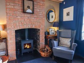 A snug with a fireplace and armchair at 2 Bredy Cottages Burton Bradstock
