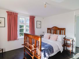 A bedroom with a bed, curtains, and a nightstand at 2 Bredy Cottages Burton Bradstock