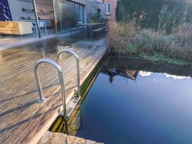A wooden deck with a swimming pool ladder and seating area at 2 Bredy Cottages in Burton Bradstock