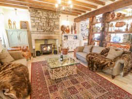 A living room with a stone fireplace a glass coffee table and two sofas at Shaftoe Mews in Haydon Bridge