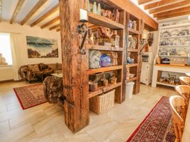 A room with wooden beams shelves displaying ceramics and decorations a sitting area with sofa and artwork on the wall at Shaftoe Mews in Haydon Bridge