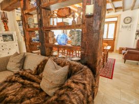 A living area with a sofa draped with a fur throw and cushions and a wooden partition with decorative objects at Shaftoe Mews in Haydon Bridge