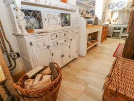 A kitchen with a white vintage cabinet a basket of firewood tile flooring and a wicker storage box at Shaftoe Mews in Haydon Bridge