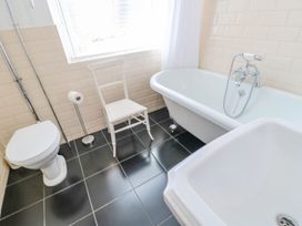 A bathroom with a toilet a white chair a clawfoot bathtub and a sink at Shaftoe Mews in Haydon Bridge