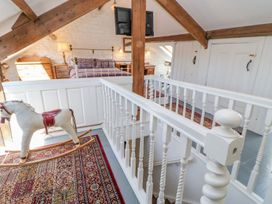 An attic bedroom with a rocking horse on a patterned rug and a bed with purple bedding at Shaftoe Mews in Haydon Bridge