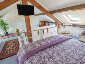 A bedroom with a patterned bedspread a white chair skylight and wooden beams at Shaftoe Mews in Haydon Bridge