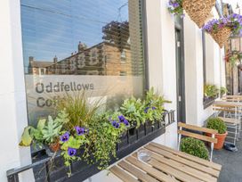 Outdoor seating area with wooden tables and chairs and flower boxes on window sills at Oddfellows Coffee