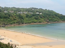 A beach with people and houses on the hill at Jaluna in Carbis Bay