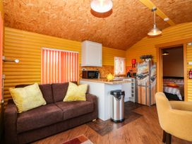 A living room with a sofa and kitchen area at Ava Lodge in West Mains near Haggerston