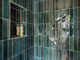 A shower with green tiles and shampoo bottles at The Old Vicarage Merriott