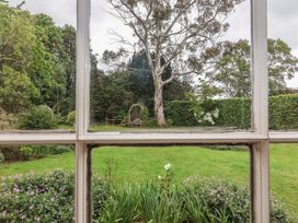 A view of a garden with trees and a bench at The Old Vicarage in Merriott
