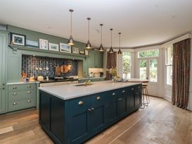 A kitchen with a central island and stools at The Old Vicarage in Merriott