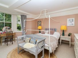 A bedroom with a bed, bench, and dressing table at The Old Vicarage in Merriott