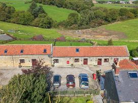 An outdoor view of a property with parked cars and green fields at Deer Pod in Staintondale near Burniston