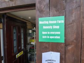 A sign for Meeting House Farm Honesty Shop with an open door in Staintondale near Burniston