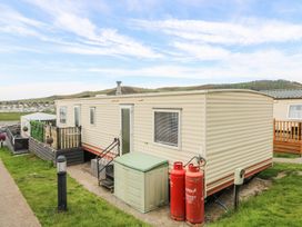 A beige mobile home with steps leading to a door and two red gas cylinders outside at GM18 in Clarach Bay near Aberystwyth