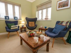 A snug room with chairs and a table featuring fruit at Corner Cottage in Preston