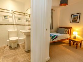 A bathroom with toilet and sink adjacent to a bedroom with bed at Corner Cottage in Preston