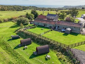 An outdoor view of a farmhouse and glamping pods at Hare Pod Staintondale near Burniston