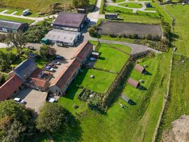 An outdoor view of a farm layout including buildings and vehicles at Woodpeckers Shepherds hut Staintondale near Burniston